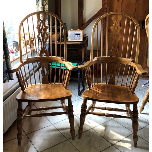 6140 - A pair of pine comb back Windsor armchairs, 119cm high, 65cm wide, with blue and white cushions (wor... 