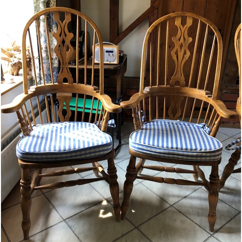 6141 - A pair of pine comb back Windsor armchairs, 119cm high, 65cm wide, with blue and white cushions (wor... 