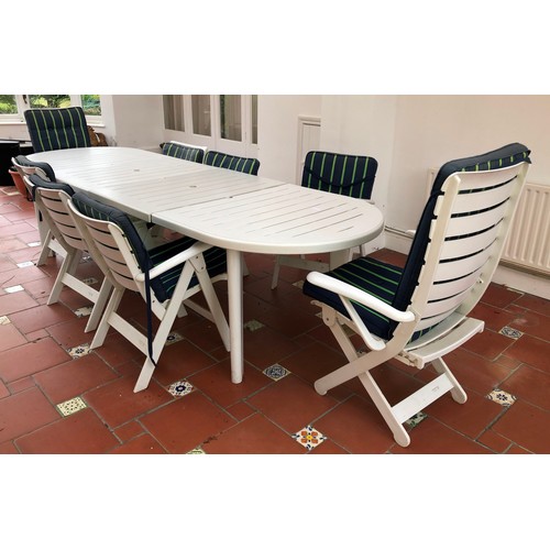 7085 - A white plastic oval garden table with 2 extending sections, and matching set of chairs, 2 large and... 