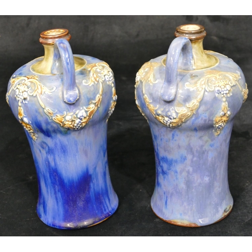 100 - A pair of Royal Doulton round bulbous thin necked jugs on blue ground with raised multicoloured swag... 