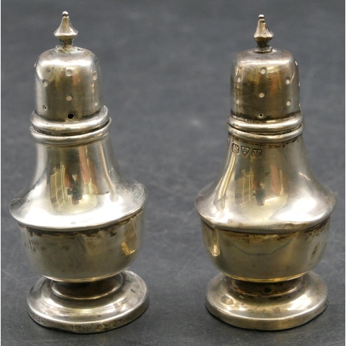 141 - A pair of Chester silver small round bulbous shaped pepper pots on sweeping bases, 7cm high