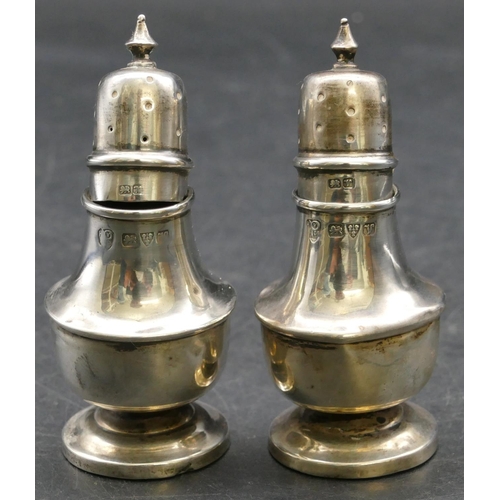 141 - A pair of Chester silver small round bulbous shaped pepper pots on sweeping bases, 7cm high