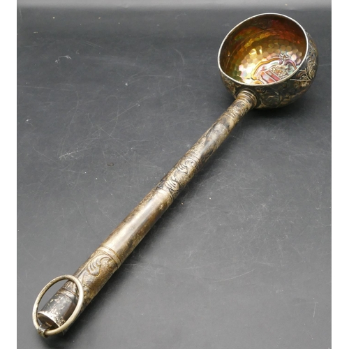 168 - An Eastern silver coloured metal ladle with part embossed leaf and scroll decoration, 47cm long, 6.6... 