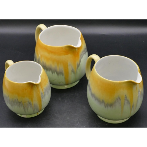 22 - A set of 3 Shelley graduated round bulbous shaped dripware jugs on pale green and yellow ground, lar... 