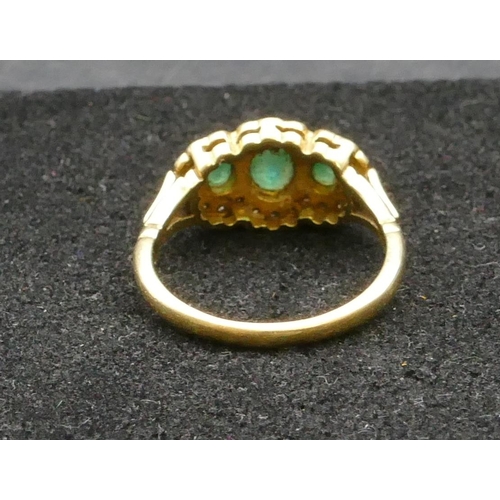 258 - An 18ct gold ladies' ring set with 3 emeralds surrounded by small diamond chips, Size P, 4.9 grams