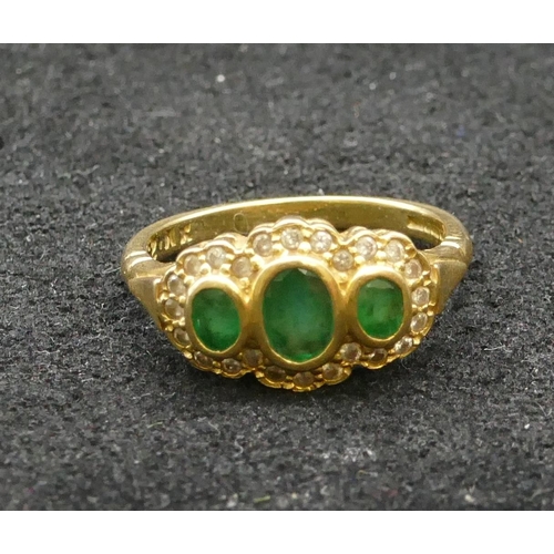 258 - An 18ct gold ladies' ring set with 3 emeralds surrounded by small diamond chips, Size P, 4.9 grams