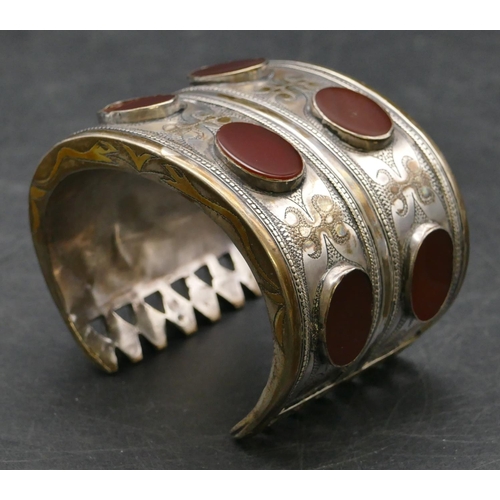 289 - An Eastern wide band bracelet mounted with oval stones and allover engraved decoration, 7.5cm wide o... 