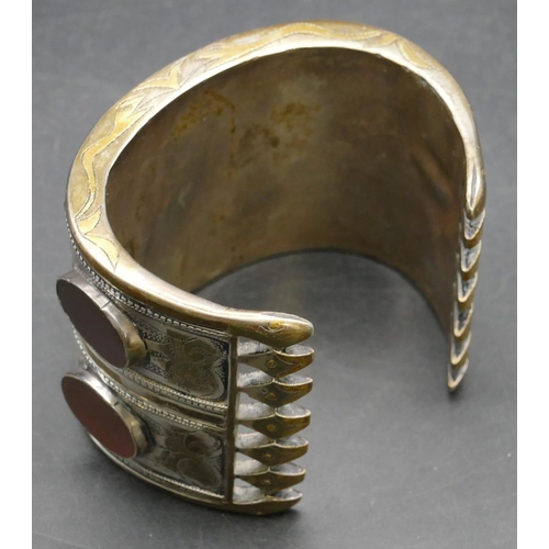 289 - An Eastern wide band bracelet mounted with oval stones and allover engraved decoration, 7.5cm wide o... 