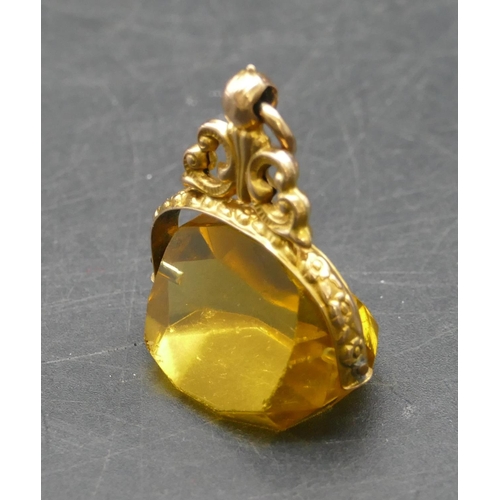 290 - A gold swivel pendant seal set with yellow triangular shaped stone with pierced and embossed decorat... 