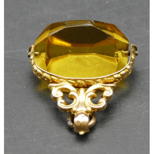 290 - A gold swivel pendant seal set with yellow triangular shaped stone with pierced and embossed decorat... 