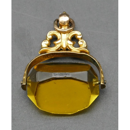 290 - A gold swivel pendant seal set with yellow triangular shaped stone with pierced and embossed decorat... 