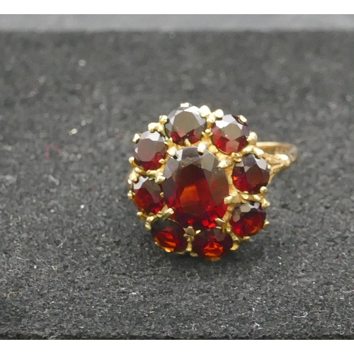 292 - A 9ct gold oval cluster ring set with centre garnet surrounded by 8 smaller garnets, Size P, 4 grams... 