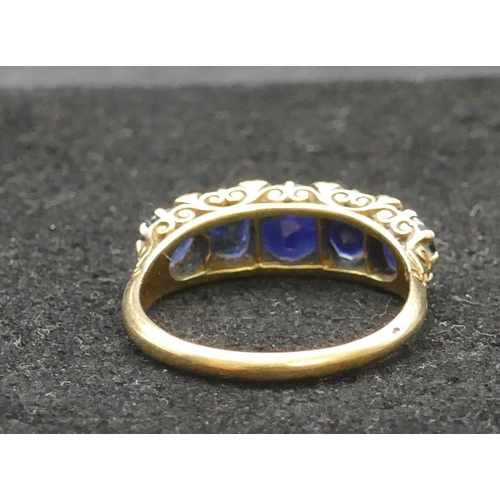 297 - An 18ct gold 5-stone graduated sapphire ring, flanked by 8 small diamond chips, Size R/S, 4.8 grams ... 