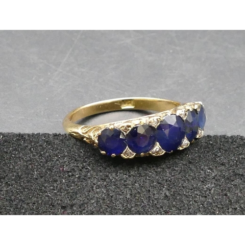 297 - An 18ct gold 5-stone graduated sapphire ring, flanked by 8 small diamond chips, Size R/S, 4.8 grams ... 