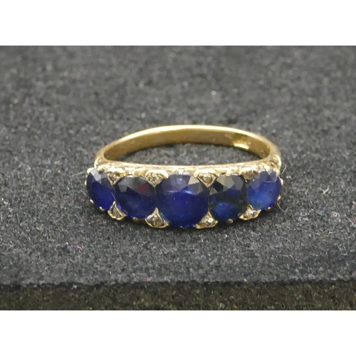 297 - An 18ct gold 5-stone graduated sapphire ring, flanked by 8 small diamond chips, Size R/S, 4.8 grams ... 