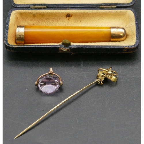 305 - A gold stick pin, a small triangular purple glass pendant seal and an amber cheroot holder with 9ct ... 