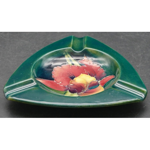 34 - A Moorcroft triangular shaped ashtray on green ground with multicoloured floral and leaf motifs to c... 