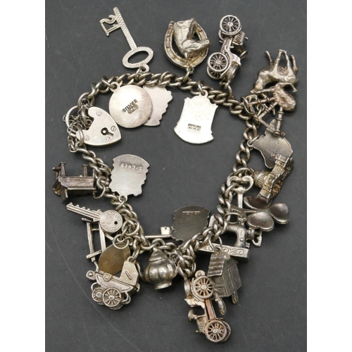 341 - A silver charm bracelet with padlock clasp mounted with 23 various charms, 66.3 grams gross