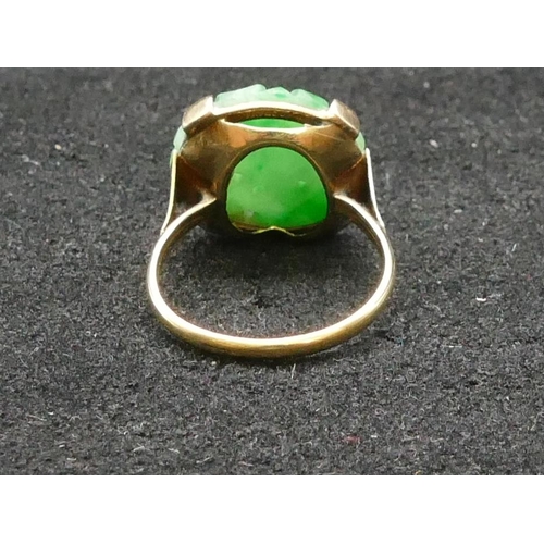 389 - An Oriental gold ring set with circular jade panel, carved and pierced floral and leaf decoration, S... 