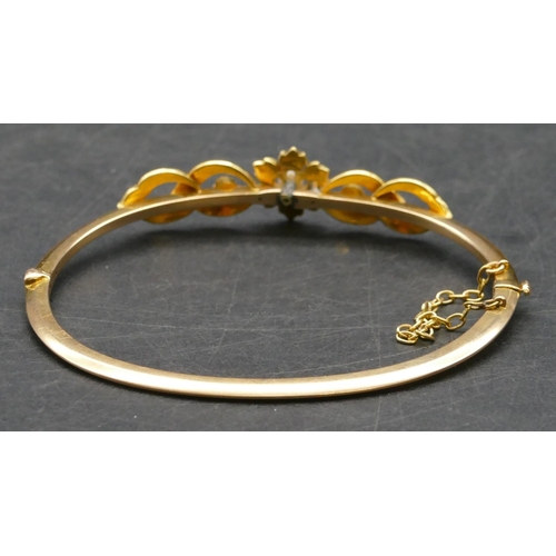 417 - A gold hinged bangle with raised Mother of Pearl motifs, 9.5 grams