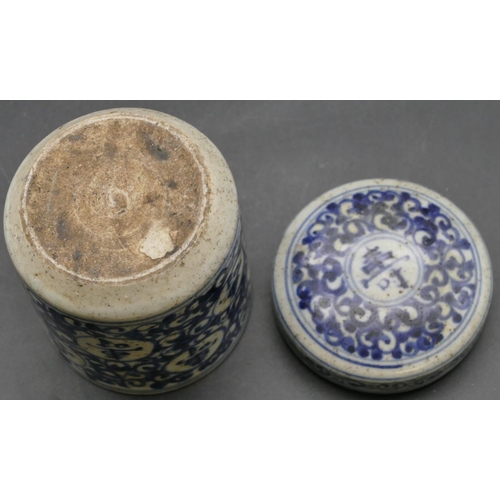 42 - An Oriental cylindrical lidded pot on blue and white ground with scroll decoration, 12.5cm high
