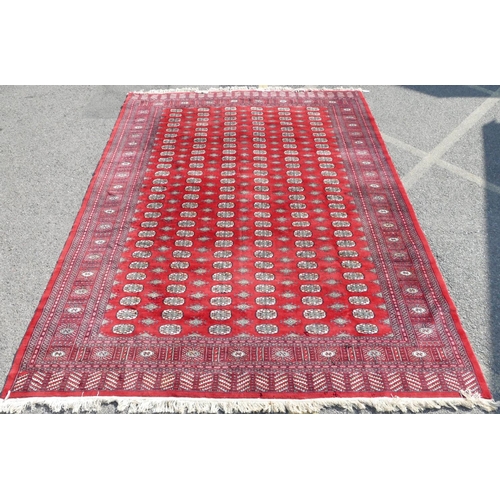 514 - A large Pakistan Bokhara rug on red ground with 6 x 27 elephant foot medallions, 342cm x 252cm