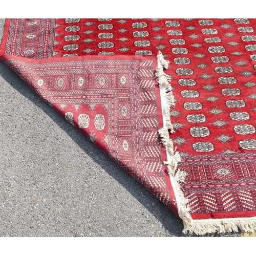 514 - A large Pakistan Bokhara rug on red ground with 6 x 27 elephant foot medallions, 342cm x 252cm