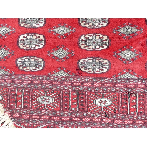 514 - A large Pakistan Bokhara rug on red ground with 6 x 27 elephant foot medallions, 342cm x 252cm