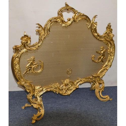 629 - A gilt metal scallop shaped fire screen with carrying handle and allover raised cupid, floral and sc... 