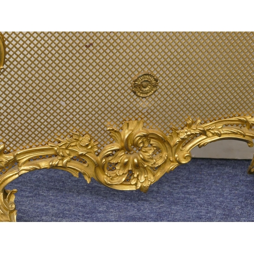 629 - A gilt metal scallop shaped fire screen with carrying handle and allover raised cupid, floral and sc... 