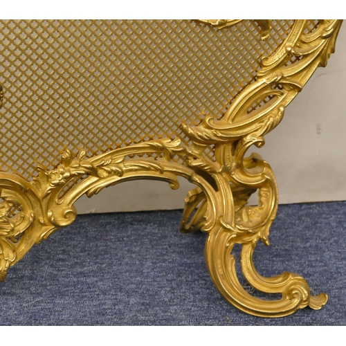 629 - A gilt metal scallop shaped fire screen with carrying handle and allover raised cupid, floral and sc... 