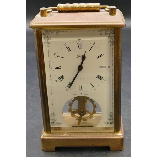 654 - A brass carriage clock with swing overhead handle, white enamelled dial and Roman numerals, fluted c... 