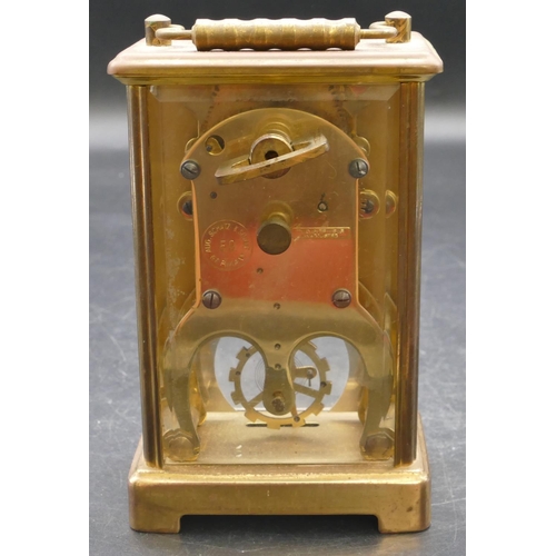 654 - A brass carriage clock with swing overhead handle, white enamelled dial and Roman numerals, fluted c... 