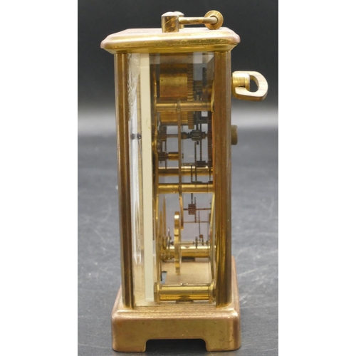 654 - A brass carriage clock with swing overhead handle, white enamelled dial and Roman numerals, fluted c... 