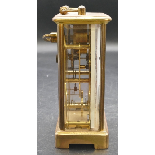 654 - A brass carriage clock with swing overhead handle, white enamelled dial and Roman numerals, fluted c... 