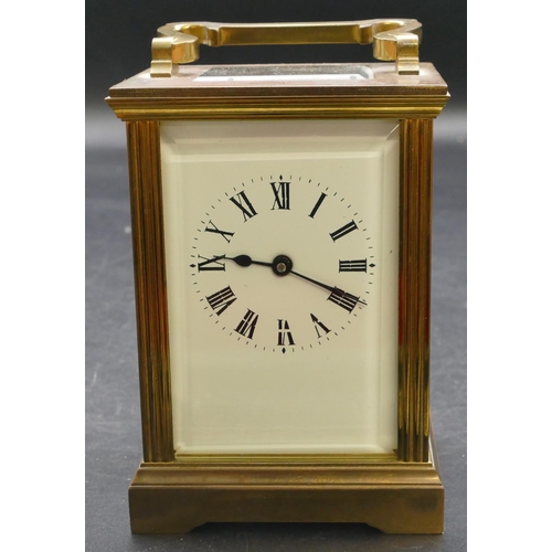 654 - A brass carriage clock with swing overhead handle, white enamelled dial and Roman numerals, fluted c... 