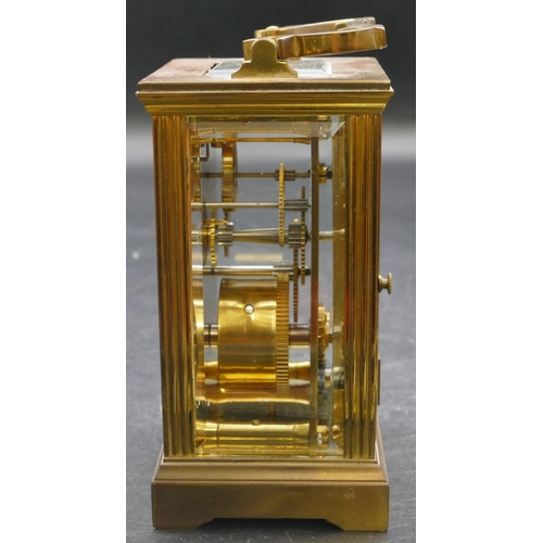 654 - A brass carriage clock with swing overhead handle, white enamelled dial and Roman numerals, fluted c... 