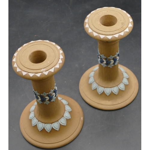 68 - A pair of Royal Doulton silicon candlesticks on round sweeping bases on brown ground with raised blu... 