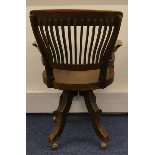 697 - An early 20th Century mahogany swivel desk chair with solid seat, spindle back, turned arms on 4 spl... 