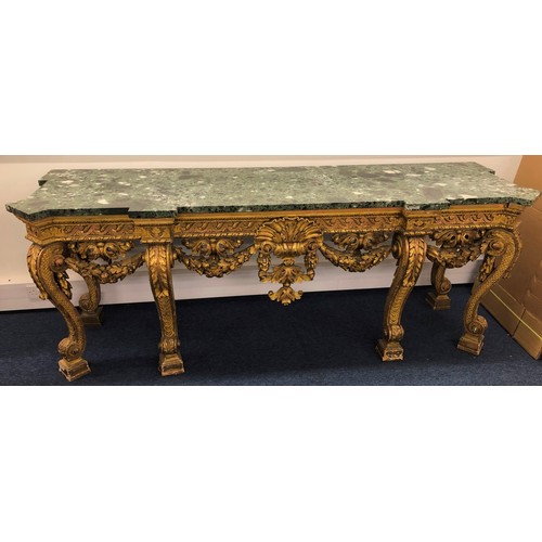 696 - An 18th Century and later carved gilt wood console table with green speckled marble top, carved frie... 