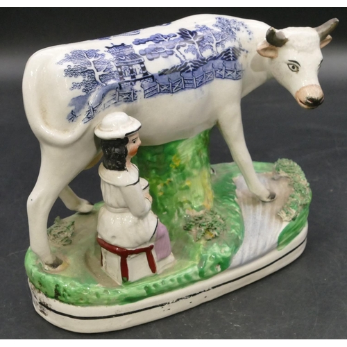 161 - A 19th Century Staffordshire group of a young maiden seated milking a cow, with blue and white decor... 