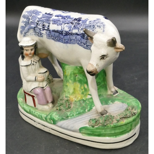 161 - A 19th Century Staffordshire group of a young maiden seated milking a cow, with blue and white decor... 