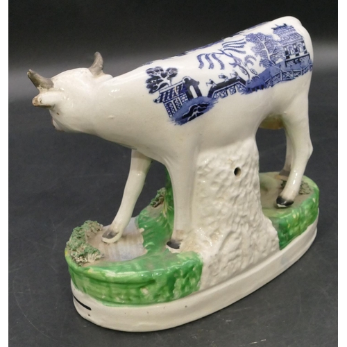 161 - A 19th Century Staffordshire group of a young maiden seated milking a cow, with blue and white decor... 