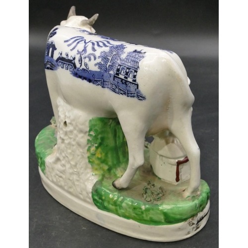 161 - A 19th Century Staffordshire group of a young maiden seated milking a cow, with blue and white decor... 