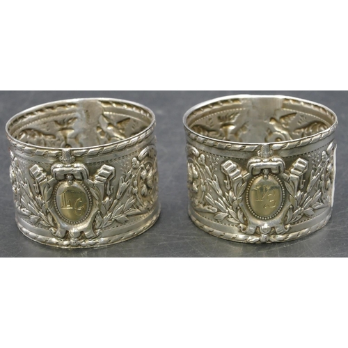 230 - A pair of Continental silver coloured metal large round napkin rings with allover embossed bird, flo... 