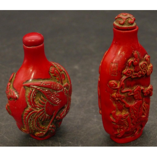 801 - 2 Oriental red snuff bottles with raised figure and animal decoration, largest 8.5cm high