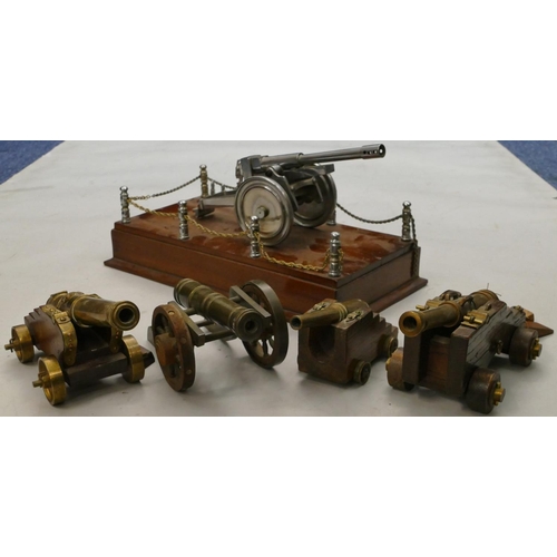 863 - 4 brass miniature table top cannons, largest 19cm long, a similar model of a cannon on a mahogany ba... 