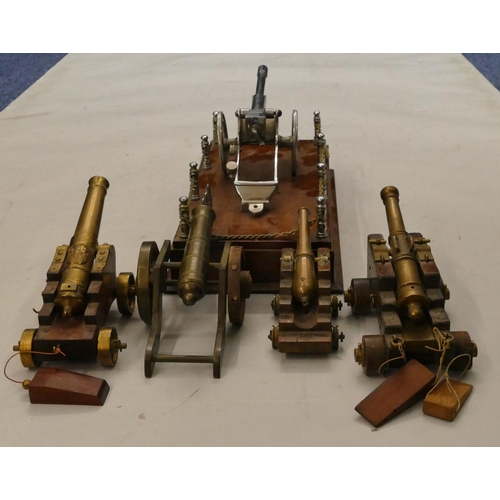 863 - 4 brass miniature table top cannons, largest 19cm long, a similar model of a cannon on a mahogany ba... 