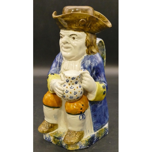 90 - An early 19th Century Staffordshire toby jug in the form of a seated gentleman in a blue jacket hold... 