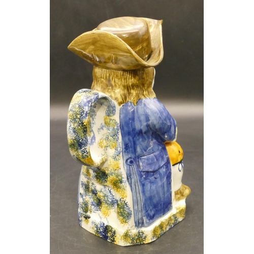 90 - An early 19th Century Staffordshire toby jug in the form of a seated gentleman in a blue jacket hold... 